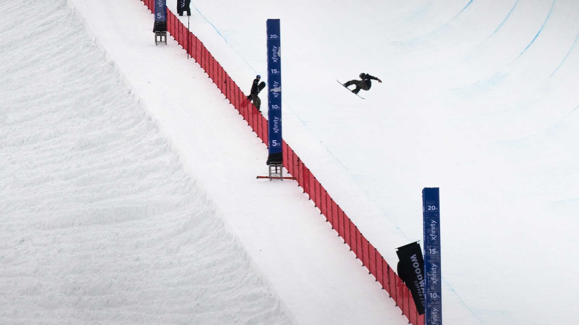 A snowboard airs in the halfpipe. 
